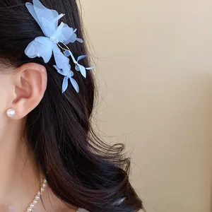 Elegant light blue fabric butterfly hair clip styled on wavy dark hair with pearls