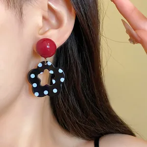 Close-up of vintage polka dot flower earrings with silver needles and red studs