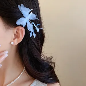 Close-up of an elegant blue fabric butterfly hair clip worn on long wavy hair