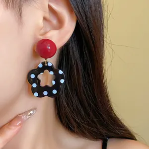 Close-up view of a model wearing retro black hollow flower earrings with white polka dots