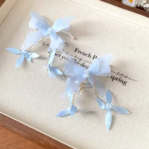 Detailed view of blue fabric butterfly hair clips with crystal beads and floral accents