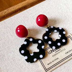 Close-up of vintage red and black polka dot flower hollow earrings on linen background