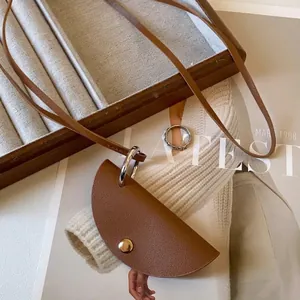 Detailed view of a minimalist brown leather pouch pendant on a long cord necklace.