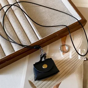 Detailed view of a mini black leather bag pendant on a trendy black cord necklace