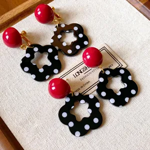 Close-up of retro red and black polka dot hollow flower earrings on linen background