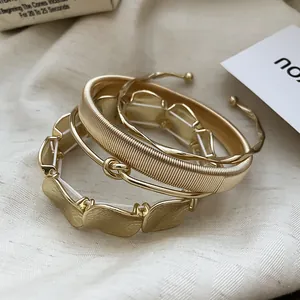 Set di quattro eleganti bracciali metallici dorati con design irregolari e texturizzati