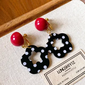 Close-up detail of retro red sphere and black polka dot hollow flower earrings.