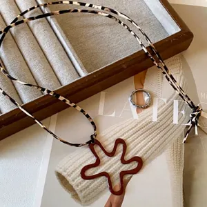 Detail view of a vintage geometric flower pendant with chic leopard print cord necklace