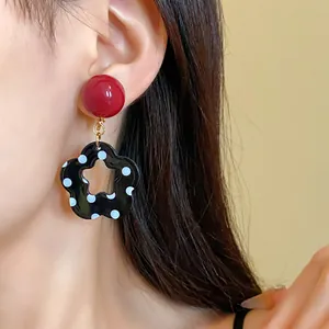 Detail shot of retro hollow flower earrings with white polka dots on model's ear