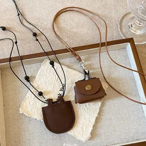 Close-up of vintage mini leather bag pendant necklaces on textured paper background.