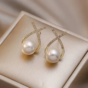 Macro detail of elegant crossover earrings with pavé crystals and white pearls