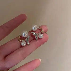 Detail view of pearl fishtail earrings with sparkling rhinestones on golden metal