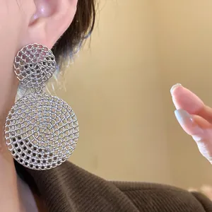 Close-up of silver hollow mesh round drop earrings on model ear, showing elegant fashion detail