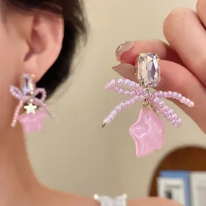 Silver needle stud earrings featuring a pearl bow and pink resin star pendant design