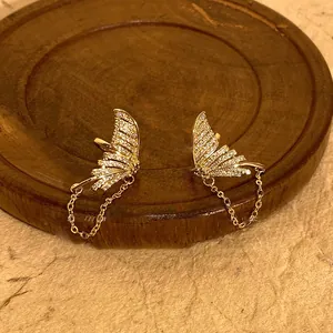 Close-up of elegant gold-toned fishtail tassel earrings with sparkly rhinestones