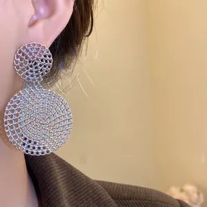 Macro detail shot of elegant silver openwork circular drop earrings worn by a model
