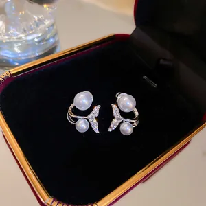 Close-up of silver-tone fishtail earrings with pearls and crystals in a luxury velvet box