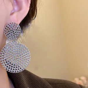 Detailed close-up showing the intricate hollow mesh texture of silver circular drop earrings
