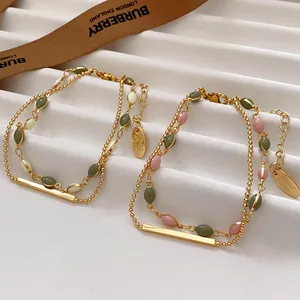 Detailed view of French vintage gold-plated layered bracelets with green and pink beads.