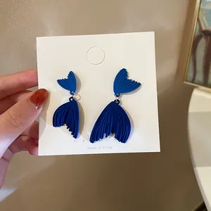 Detail view of deep blue matte mermaid tail tassel earrings on a white display card.