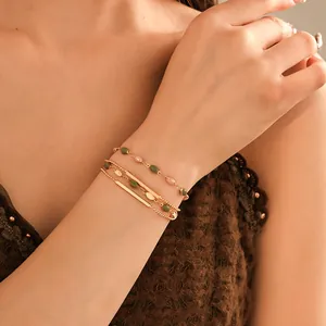 Close-up of French vintage gold-plated layered bracelet with green beads and bars.
