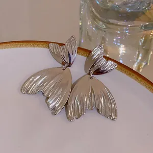 Close-up detail of silver fishtail earrings with elegant metallic texture and fan shape