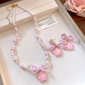 Detailed view of pink resin star and pearl bow necklace and earrings set for women