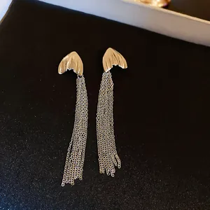 Elegant silver fishtail earrings featuring long metallic chain tassels on black