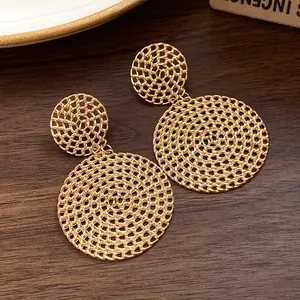 Detailed close-up of gold-plated mesh round pendant earrings on a wood background