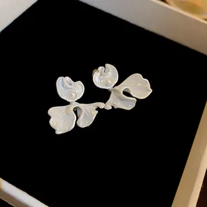 Detail view of elegant white floral stud earrings with central pearl on velvet