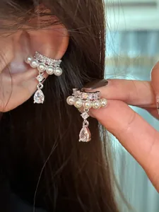 Macro view of elegant silver ear cuffs with pearls and zircon water-drop pendants