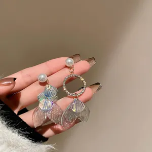 Detailed close-up of asymmetrical mermaid tail earrings with pearls and crystals