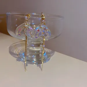 Close-up of iridescent mermaid tail tassel earrings with rhinestones and crystals.