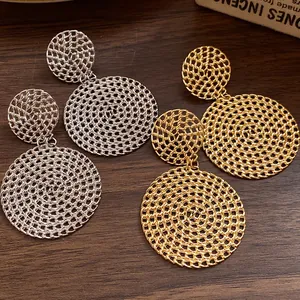 Detailed macro view of elegant gold and silver hollow woven circular drop earrings on wood