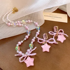 Detail view of pink pearl jewelry set with resin stars and bow accents.