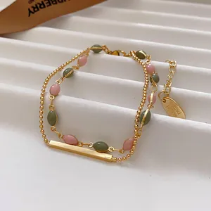 Close-up of a double-layer vintage gold bracelet with pink and green stones