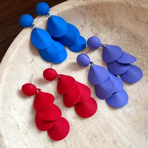 Nahaufnahme matt lackierter, mehrlagiger Quastenohrringe in den Farben Blau, Rot, Lila