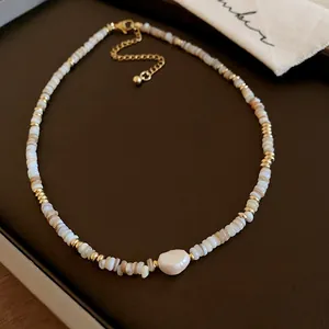 Macro view of a minimalist beaded necklace featuring a central irregular pearl and gold accents