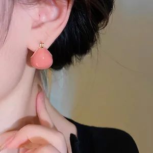 Elegant vintage pink enamel bean-shaped stud earrings worn by a model for chic look