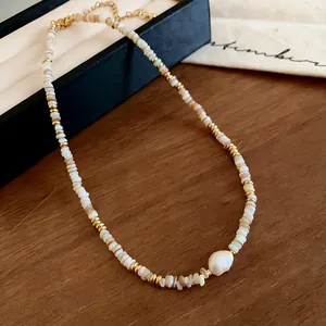 Detailed close-up of a shell bead necklace with a baroque pearl and gold accents.