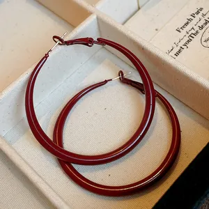 Close-up of burgundy drip oil hoop earrings with silver needles in a jewelry box