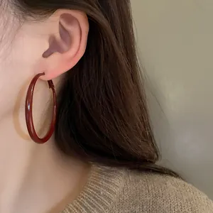 Detailed close-up view of oversized vintage red enamel hoop earrings worn by a model