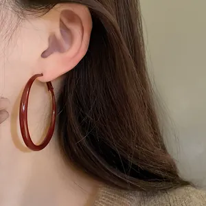Close-up detail of a large burgundy enamel hoop earring on a model for a vintage look