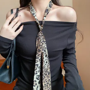 Close-up of a leopard print scarf necklace paired with a stylish black shoulder top.