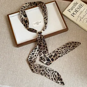 Elegant detail of a leopard print silk scarf necklace displayed on a wooden tray