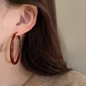 Close-up view of elegant red enamel hoop earrings featuring silver needles in a retro style