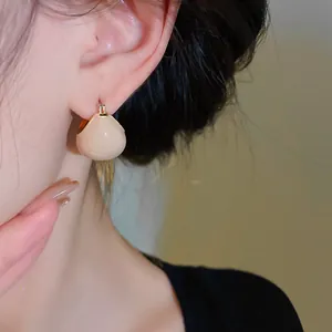Close-up view of elegant vintage gold-plated drop oil bean earrings worn by model
