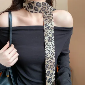 Detail view of a stylish leopard print silk scarf necklace worn with an off-shoulder top