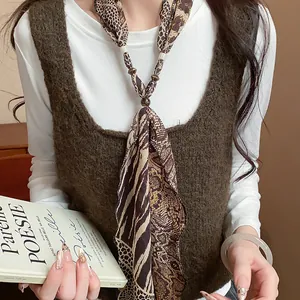 Detailed macro view of the leopard and python print scarf necklace worn by a model.