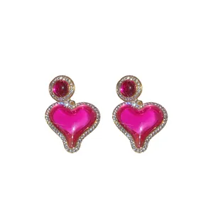 Boucles d'oreilles cœur en résine rose élégantes avec des strass brillants style vintage.